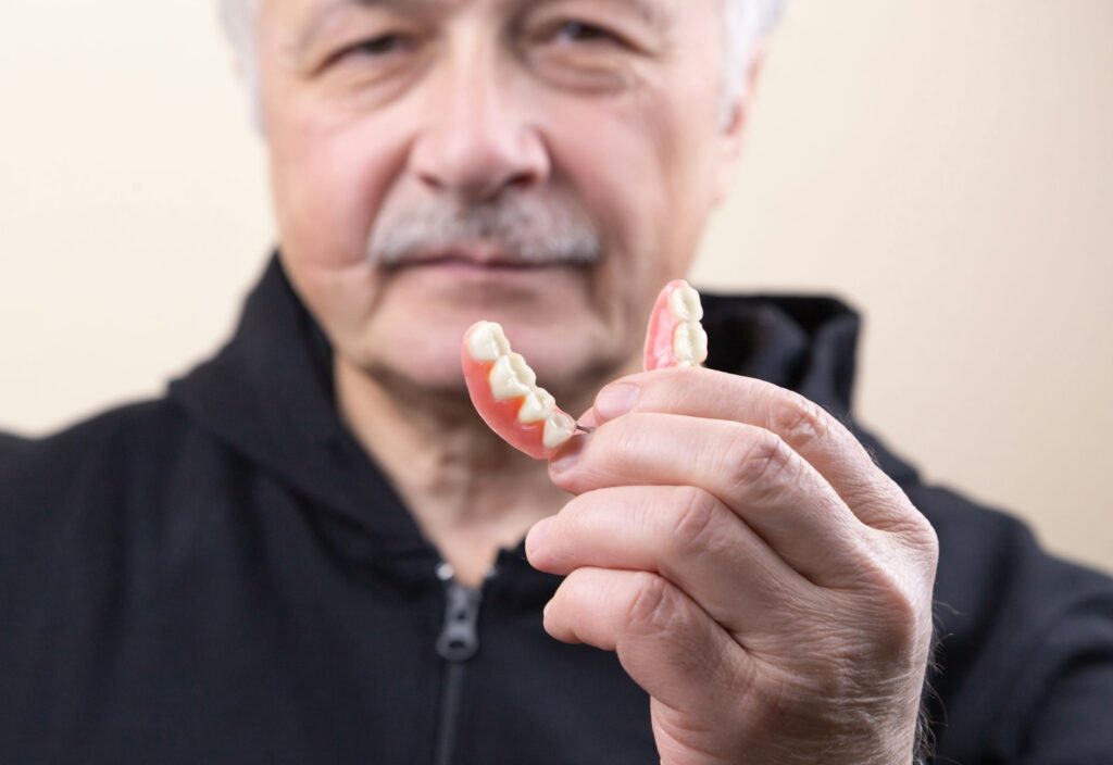 Senior man holding a denture